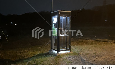 Public phone booth glowing in the countryside at night 112730517