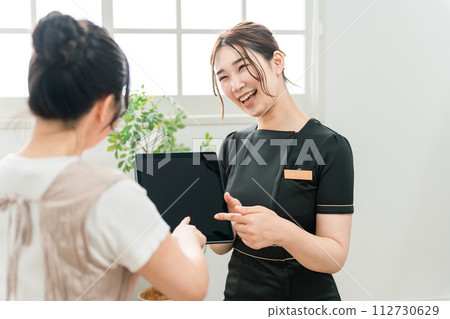 在美容院使用平板電腦進行諮詢 112730629