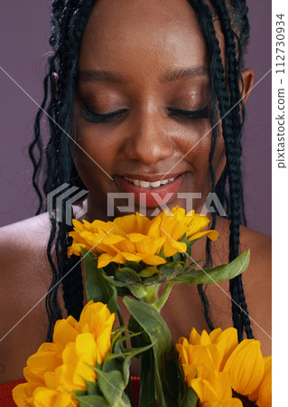 Happy Black woman smelling flowers sent by her date 112730934