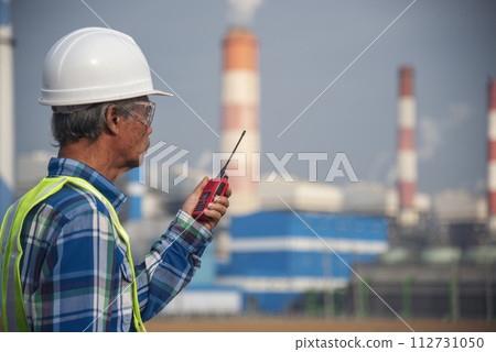 Senior Electrician engineer man hand holding red Walkie talkie communicate wear White hardhat at Power stations manufacturing electrical plant. Technician worker blue hard hat helmet Engineer industry Senior Electrician engineer man hand holding red Walkie talkie communicate wear White hardhat at Power stations manufacturing electrical plant. Technician worker blue hard hat helmet Engineer industry 112731050