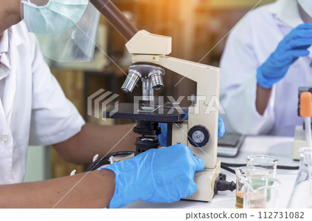 Scientist man look into Microscope research in science laboratory. Asian scientist looking equipment laboratory chemistry labs. Covid-19 coronavirus biochemistry research experiment vaccine concept Scientist man look into Microscope research in science laboratory. Asian scientist looking equipment laboratory chemistry labs. Covid-19 coronavirus biochemistry research experiment vaccine concept 112731082