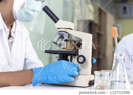Scientist man look into Microscope research in science laboratory. Asian scientist looking equipment laboratory chemistry labs. Covid-19 coronavirus biochemistry research experiment vaccine concept 112731090