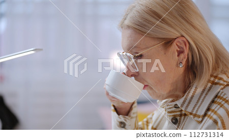 A senior woman is enjoying a cup of coffee while working at home as an IT specialist 112731314