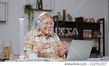A senior woman is laughing while having an online lesson, participating in distance education through a video conference call A senior woman is laughing while having an online lesson, participating in distance education through a video conference call 112731337