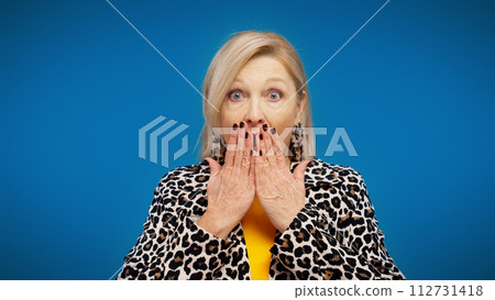 A stylish senior woman is disappointed with bad news and is covering her mouth with her hands 112731418