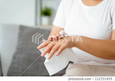 A woman is wiping her hands with a paper towel 112731455