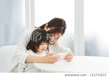 Girl looking at smartphone with mom 112731672