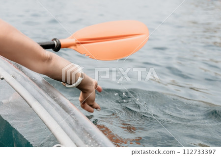 Woman in kayak back view. Happy young woman with long hair floating in transparent kayak on the crystal clear sea. Summer holiday vacation and cheerful female people relaxing having fun on the boat Woman in kayak back view. Happy young woman with long hair floating in transparent kayak on the crystal clear sea. Summer holiday vacation and cheerful female people relaxing having fun on the boat 112733397