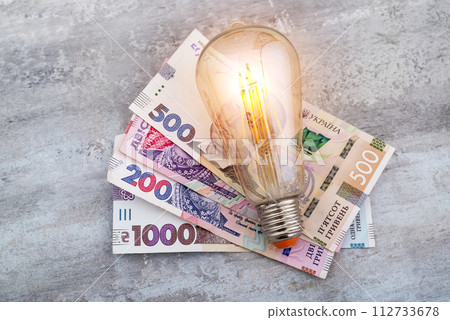 Ukrainian money hryvnias and a light bulb. The concept of increasing electricity prices in Ukraine and the deficit. Electricity costs 112733678