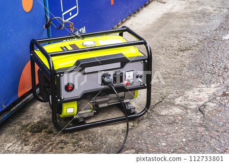 Portable electric generator running in the cold winter.Energy genocide. Power outage as a result of missile strikes by Russia on energy facilities of Ukraine. Small business use gasoline generators 112733801