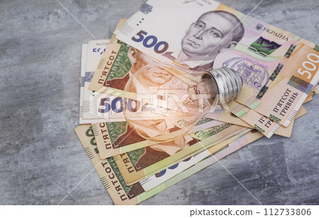 Ukrainian money hryvnias and a light bulb. The concept of increasing electricity prices in Ukraine and the deficit. Electricity costs Ukrainian money hryvnias and a light bulb. The concept of increasing electricity prices in Ukraine and the deficit. Electricity costs 112733806