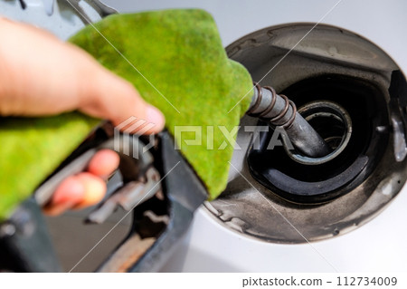 hand refilling a car with fuel at a gas station 112734009