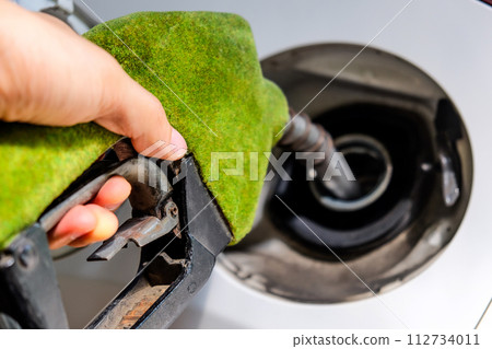 hand refilling a car with fuel at a gas station 112734011