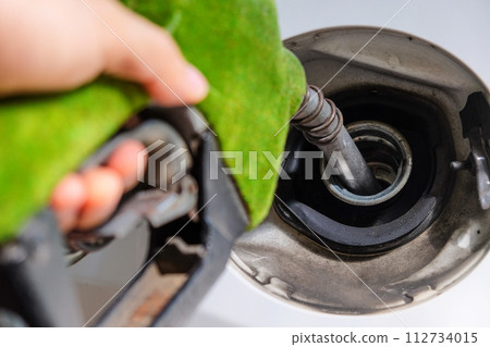 hand refilling a car with fuel at a gas station hand refilling a car with fuel at a gas station 112734015