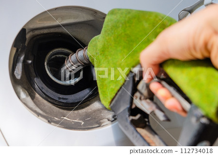 hand refilling a car with fuel at a gas station 112734018