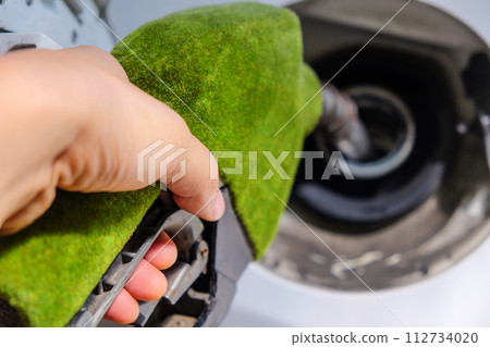 hand refilling a car with fuel at a gas station 112734020