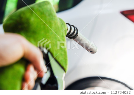 hand refilling a car with fuel at a gas station 112734022