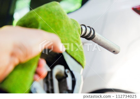 hand refilling a car with fuel at a gas station hand refilling a car with fuel at a gas station 112734025