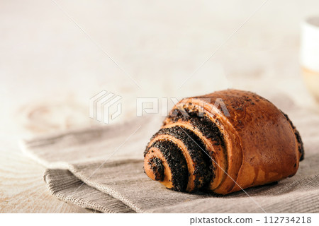 bun with poppy seeds on light wood background with copy space 112734218