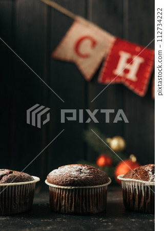 chocolate muffins with powdered sugar on top on a black background. Christmas decoration . Still life close up. Food photo 112734222