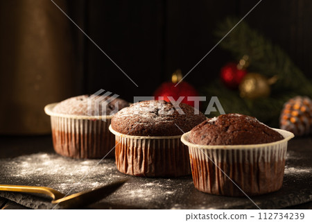 chocolate muffins with powdered sugar on top on a black background. Christmas decoration . Still life close up. Food photo. 112734239