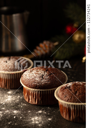 chocolate muffins with powdered sugar on top on a black background. Christmas decoration . Still life close up. Food photo. chocolate muffins with powdered sugar on top on a black background. Christmas decoration . Still life close up. Food photo. 112734241