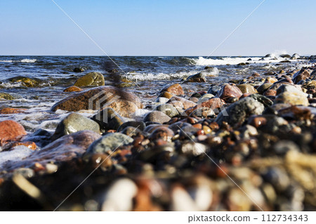 The sea wave beats against a stone on the shore. Blue sea and rocky shore 112734343