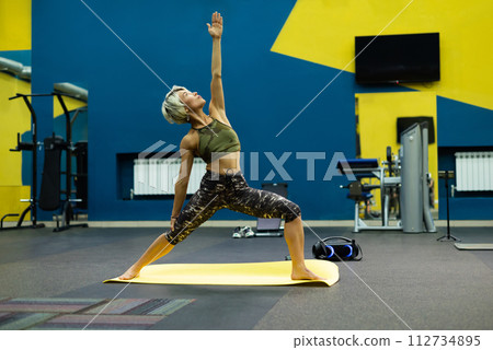 a slender athletic woman in the gym is beautifully engaged in yoga exercises on a mat 112734895