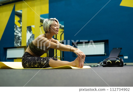 a slender athletic woman in the gym is beautifully engaged in yoga exercises on a mat a slender athletic woman in the gym is beautifully engaged in yoga exercises on a mat 112734902