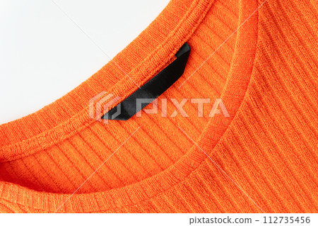 A close-up of the orange ribbed sweater's neckline, highlighting the texture and quality of the fabric. A close-up of the orange ribbed sweater's neckline, highlighting the texture and quality of the fabric. 112735456