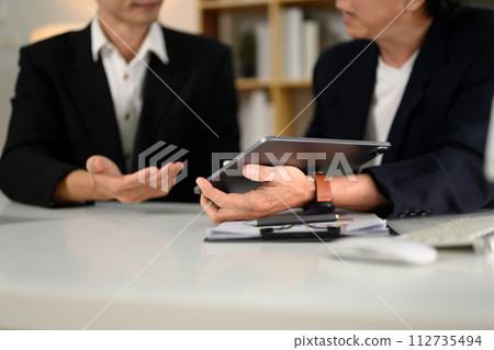 Professional businesspeople analyzing marketing data on digital tablet at office Professional businesspeople analyzing marketing data on digital tablet at office 112735494