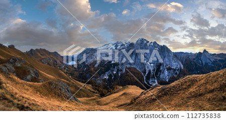 Autumn Dolomites mountain scene from hiking path betwen Pordoi Pass and Fedaia Lake, Italy. Snowy Marmolada Glacier and Fedaia Lake in far. 112735838