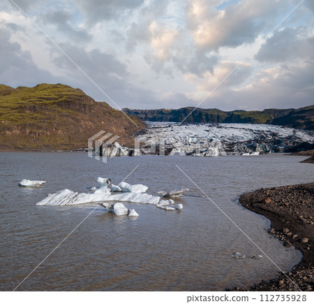 Soheimajokull picturesque glacier in southern Iceland. The tongue of this glacier slides from the volcano Katla. Beautiful glacial lake lagoon with blocks of ice and surrounding mountains. 112735928