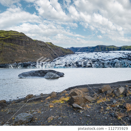 Soheimajokull picturesque glacier in southern Iceland. The tongue of this glacier slides from the volcano Katla. Beautiful glacial lake lagoon with blocks of ice and surrounding mountains. Soheimajokull picturesque glacier in southern Iceland. The tongue of this glacier slides from the volcano Katla. Beautiful glacial lake lagoon with blocks of ice and surrounding mountains. 112735929