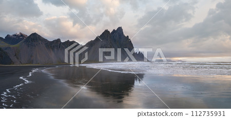 Sunrise Stokksnes cape sea beach and Vestrahorn Mountain with its reflection on wet black volcanic sand surface, Iceland. Amazing nature scenery, popular travel destination. Sunrise Stokksnes cape sea beach and Vestrahorn Mountain with its reflection on wet black volcanic sand surface, Iceland. Amazing nature scenery, popular travel destination. 112735931