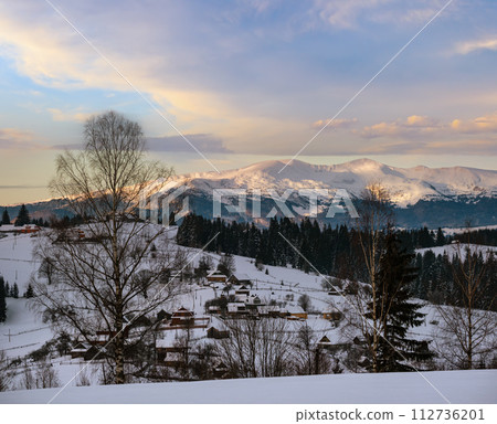 Small alpine village and winter snowy mountains in first sunrise sunlight around, Voronenko, Carpathian, Ukraine. 112736201