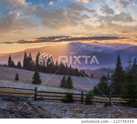 Picturesque sunset above late autumn mountain countryside.  Ukraine, Carpathian Mountains. Peaceful traveling, seasonal, nature and countryside beauty concept scene. 112736354