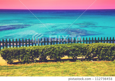 Seascape in summer evening. Wooden fence on the embankment 112736458