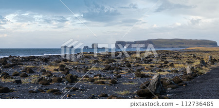 Picturesque autumn Dyrholaey Cape and rock formations view from Reynisfjara ocean black volcanic sand beach. Vik, South Iceland. Picturesque autumn Dyrholaey Cape and rock formations view from Reynisfjara ocean black volcanic sand beach. Vik, South Iceland. 112736485