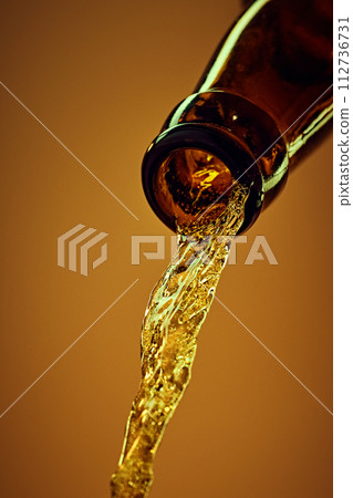 Close-up of beer bottle with condensation water drops, with chill lager beer pouring against yellow background Close-up of beer bottle with condensation water drops, with chill lager beer pouring against yellow background 112736731