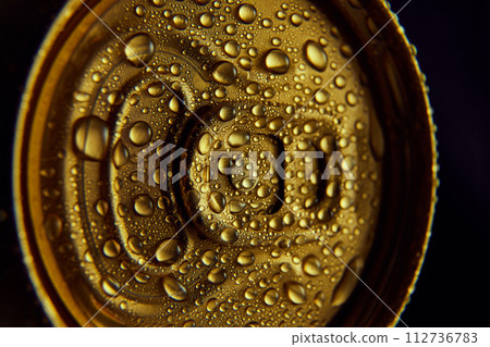 Close-up photo of golden aluminum closed can, jar of beer, coke, soda with condensation water drops against black background. 112736783