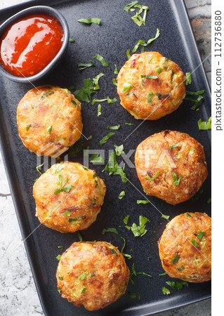 Indonesian fried croquettes perkedel made of mashed potatoes and minced meat with sauce closeup on the plate on the table. Vertical top view 112736880