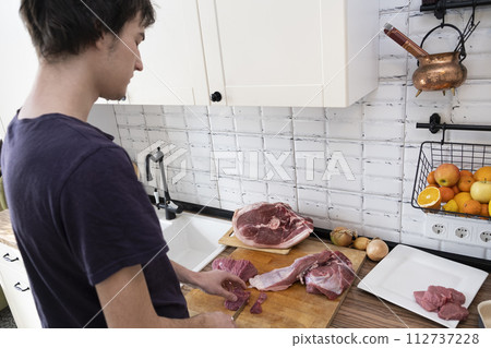 Real men cutting fresh raw meat on board in white kitchen. Preparing pork meat, cooking Real men cutting fresh raw meat on board in white kitchen. Preparing pork meat, cooking 112737228