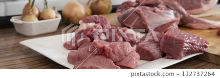 Peases of meat, cutting fresh raw meat on board in white kitchen. Banner, Preparing pork meat, cooking 112737264