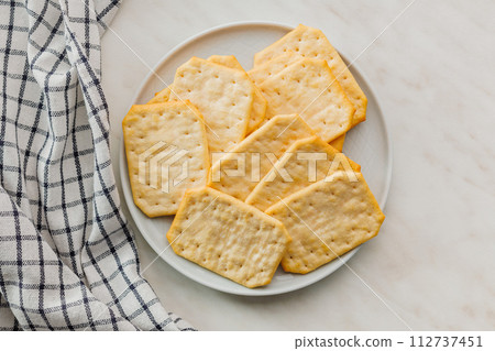 Golden Baked Crackers on plate on a White kitchen table. Top view. 112737451