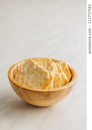 Golden Baked Crackers in bowl on a White kitchen table. Golden Baked Crackers in bowl on a White kitchen table. 112737482