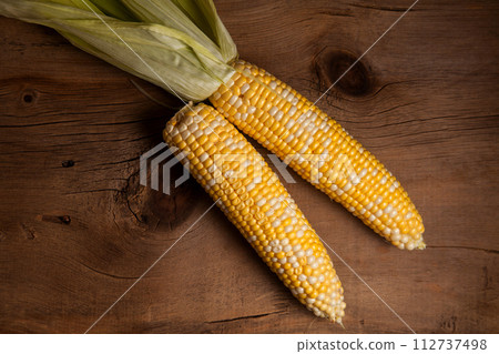 Two cobs sweet corn on wooden background.. Two cobs sweet corn on wooden background.. 112737498