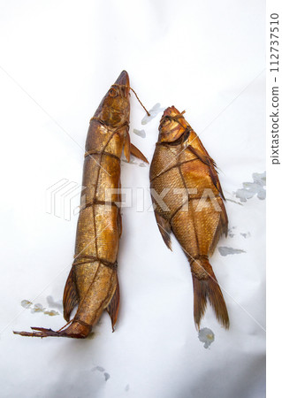 Smoked freshwater pike and common bream fish for home use on white paper.. 112737510