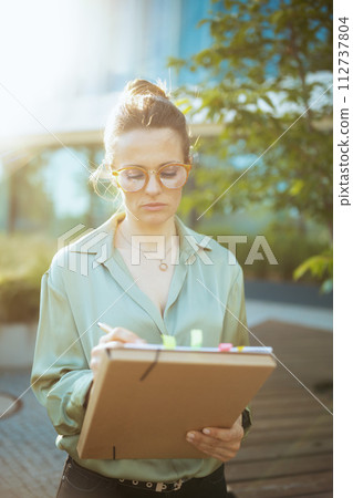 pensive modern woman worker in green blouse and eyeglasses 112737804