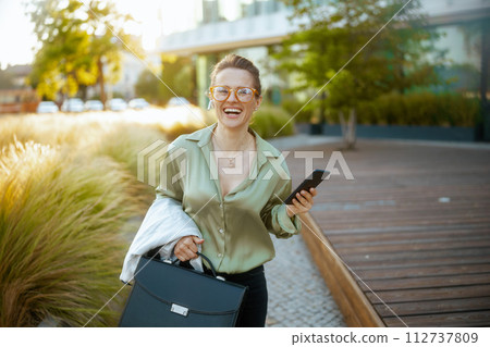 smiling woman employee in green blouse and eyeglasses walking 112737809